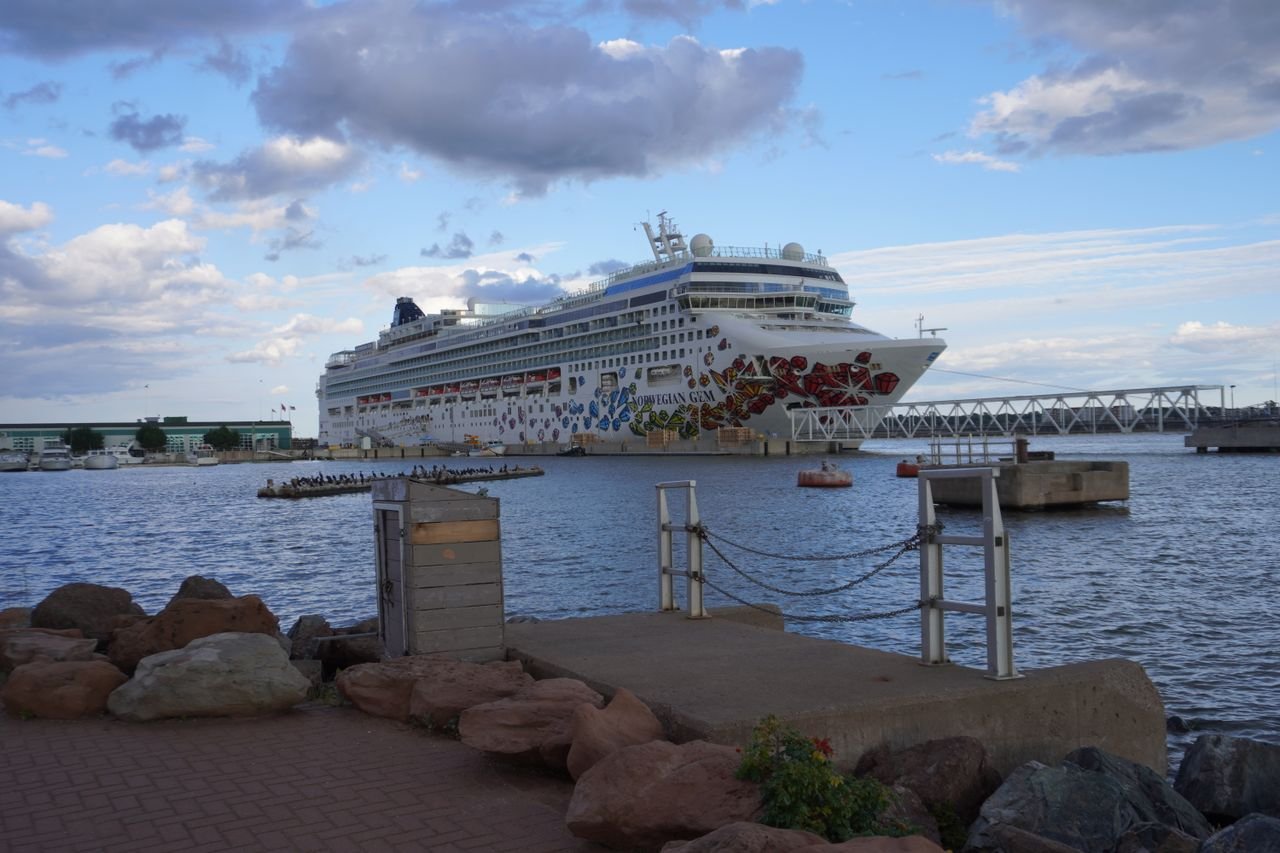A large, decorated cruise ship docked at a port under a bright sky.