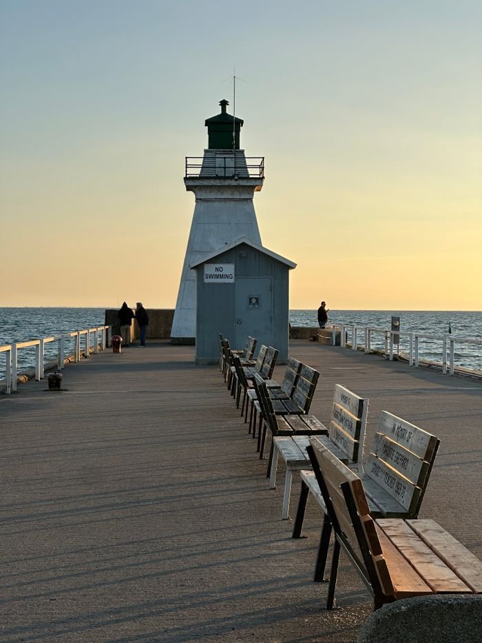 Tranquil sunset view at Port Dover lighthouse with benches along the pier.