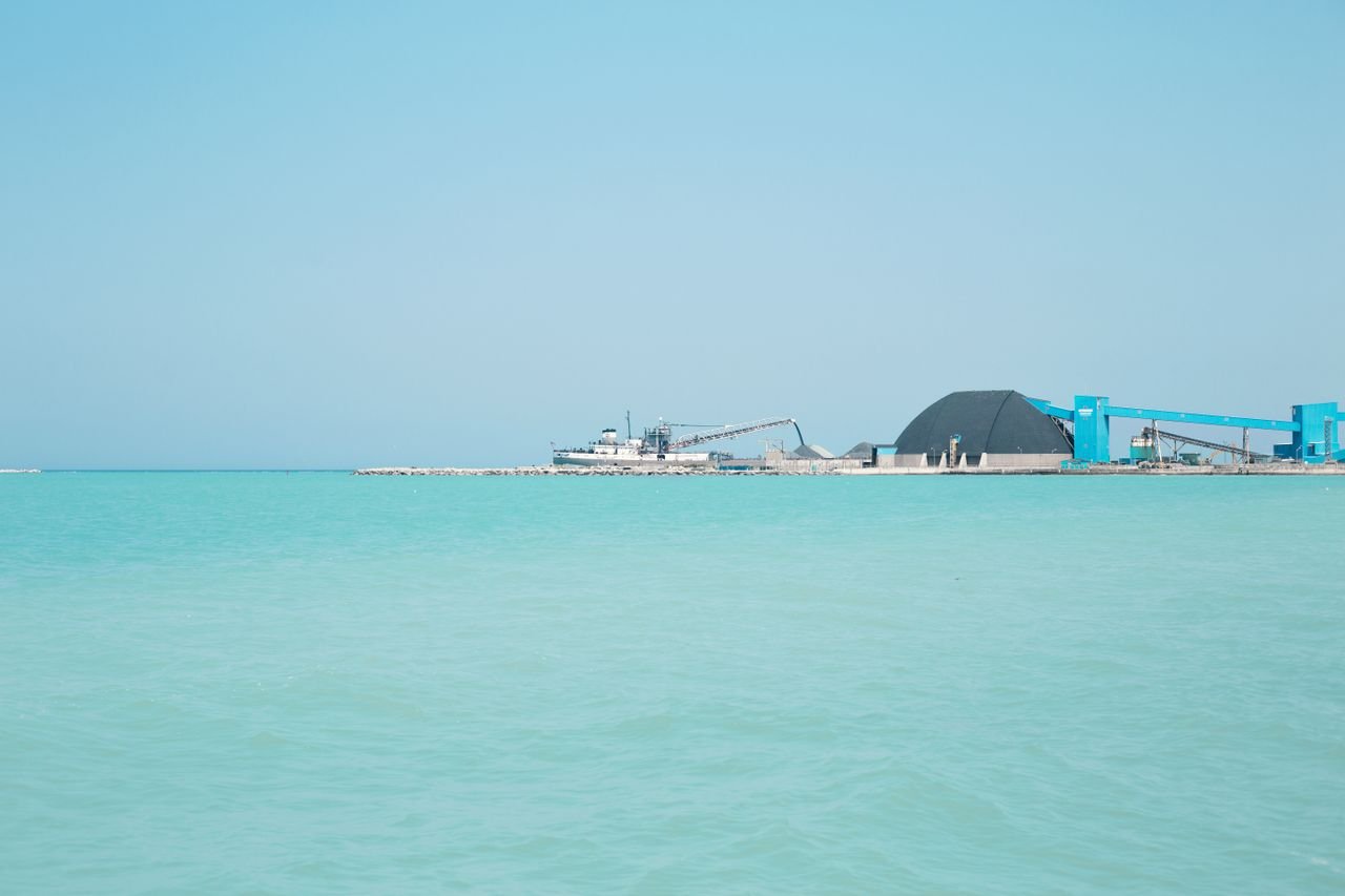 A scenic view of the industrial harbor in Goderich with blue water and clear skies.