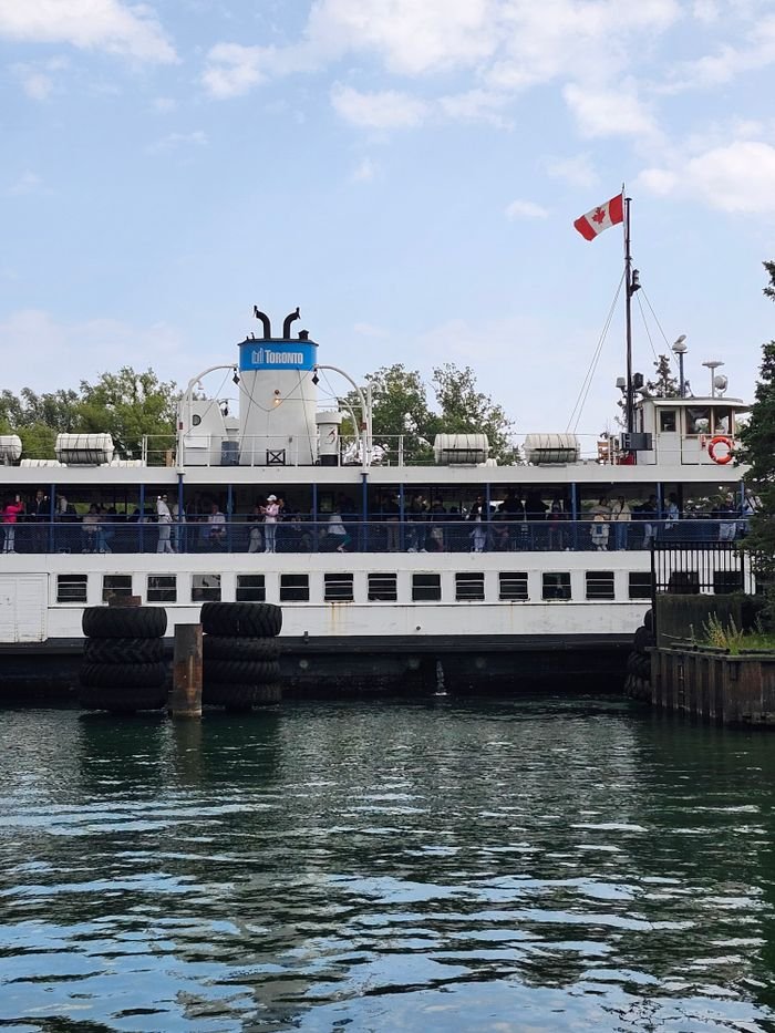 Toronto Island Ferry at the dock with clear skies and water reflection.