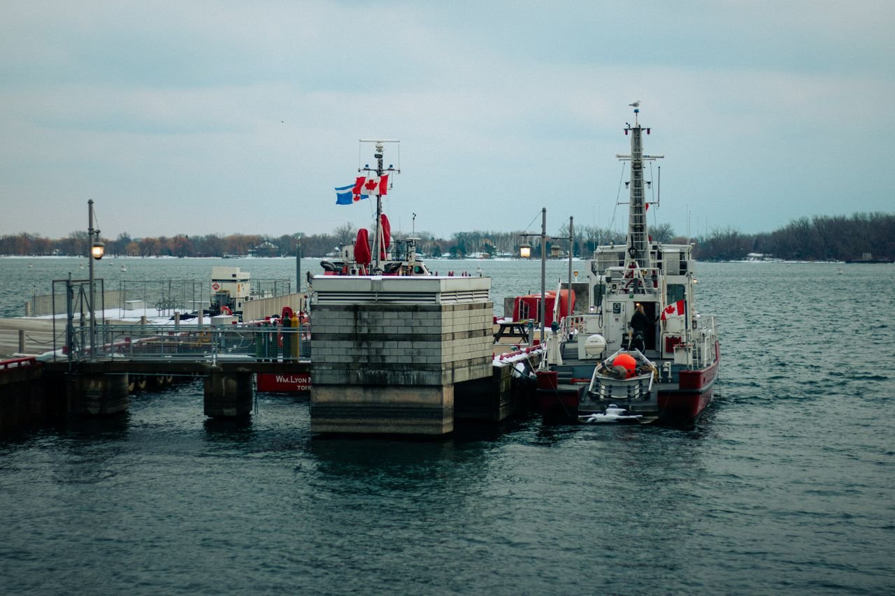digital View of ships docked at Torontos waterfront during winter, with Canadian flags flying.